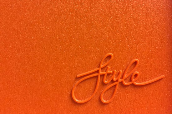 The word 'style' in a raised, rubbery texture, against an orange rubber background
